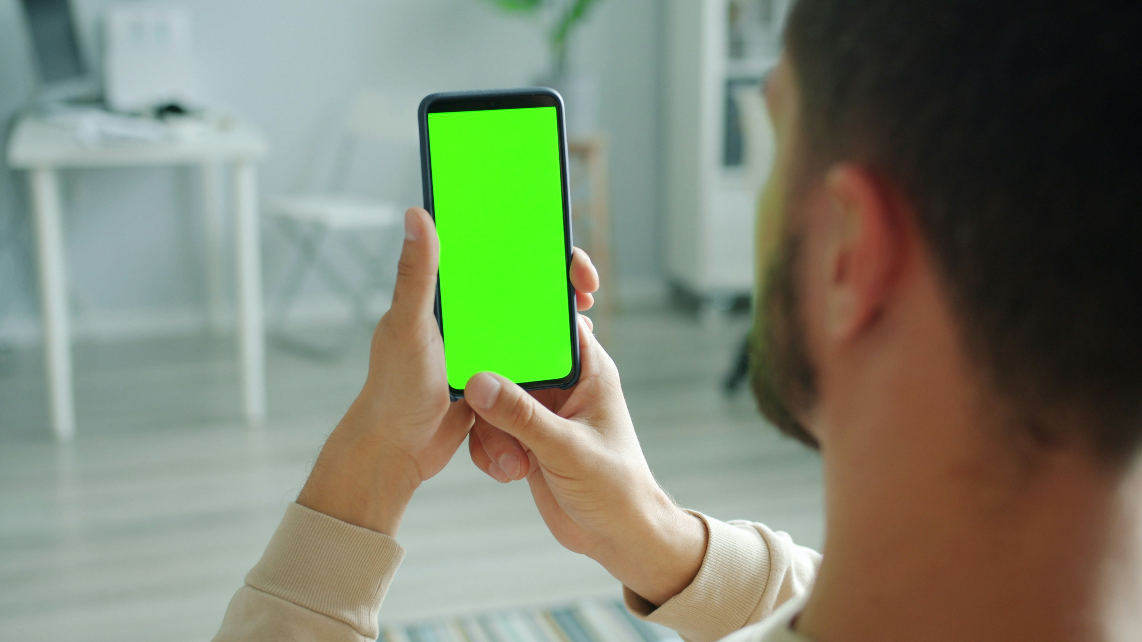 Mobile app user interface design - male hand swiping smartphone with green screen touching browsing enjoying content in social media. Contemporary technology and gadgets concept.