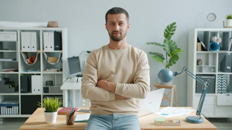 Man with arms crossed in modern office workspace.