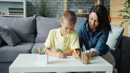 Mother and son drawing together at a table.