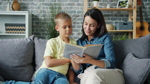 Mother and son reading a book together on sofa.