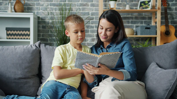 Mother and son reading a book together on sofa.