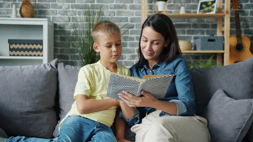 Mother and son reading a book together on sofa.