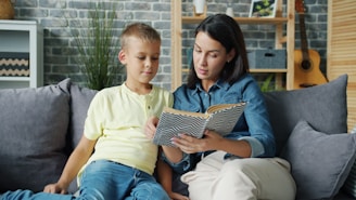 Mother and son reading a book together on the couch.