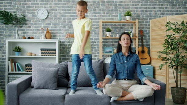 Mother meditates while son dances on couch