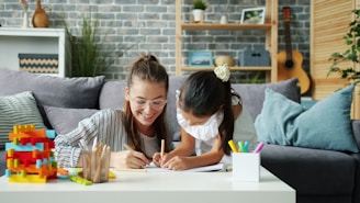 Woman and child drawing together on a couch.