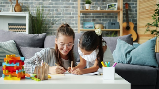 Woman and child drawing together on a couch.