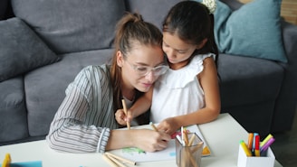 Mother and daughter drawing together at a table.