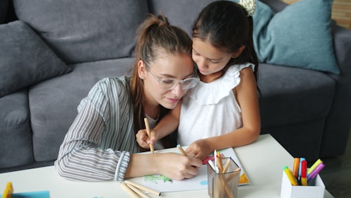 Mother and daughter drawing together at a table.
