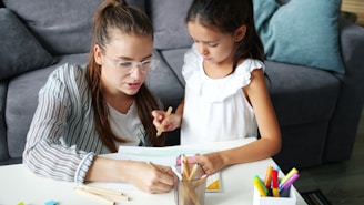 Mother and daughter drawing together at a table.