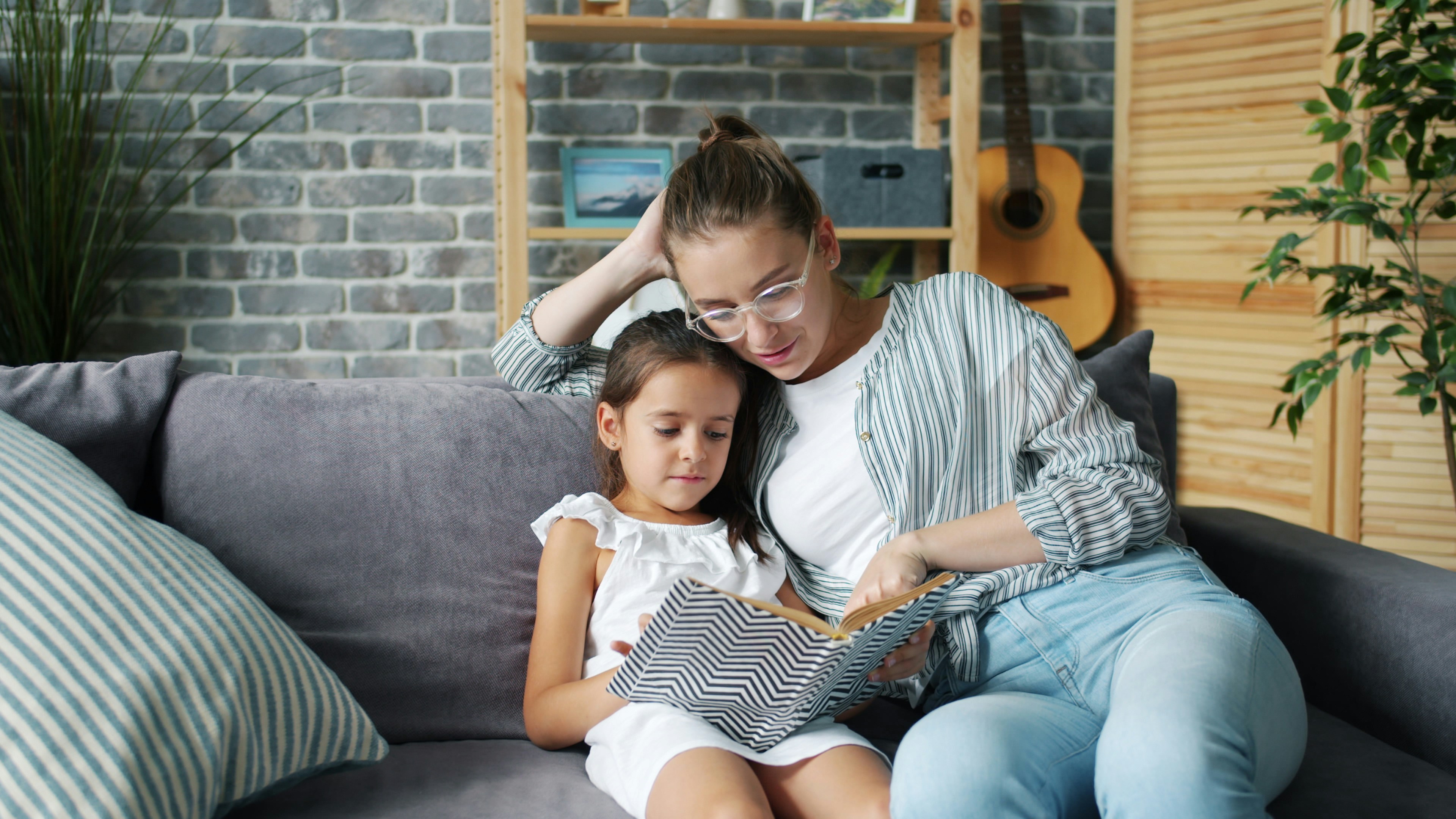 Mother and daughter reading together on couch