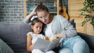 Mother and daughter reading a book together on sofa