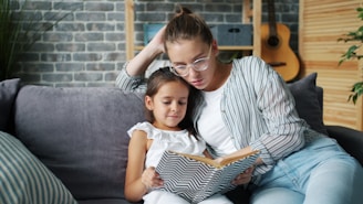 Mother and daughter reading a book together on couch