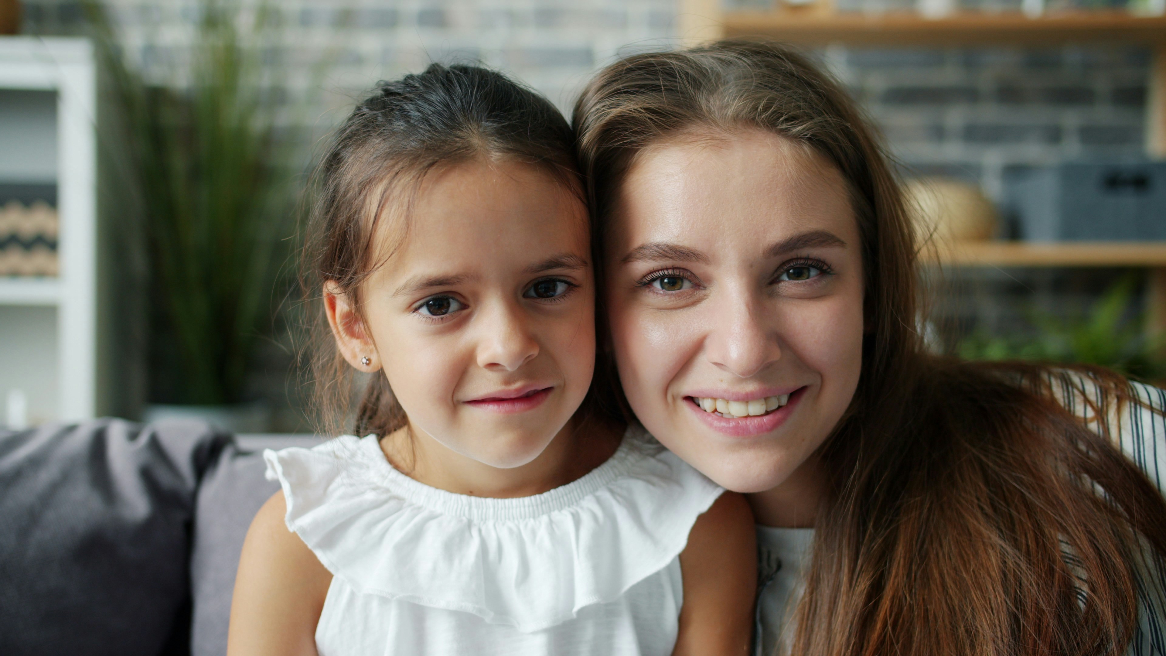 Mother and daughter smiling together on a couch.