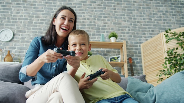 Mother and son playing video games together on couch