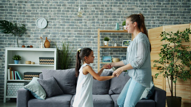 Mother and daughter dancing together in living room.