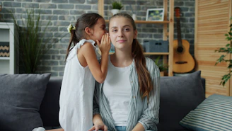 Girl whispers a secret into a woman's ear