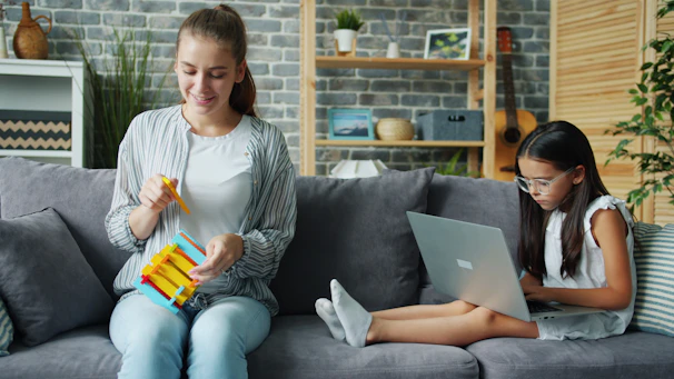 Woman and girl on couch with laptop and toy.