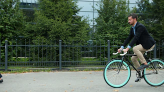 Man riding bicycle past woman on sidewalk