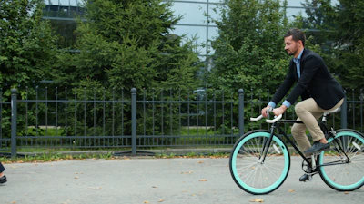 Man riding bicycle past woman on sidewalk