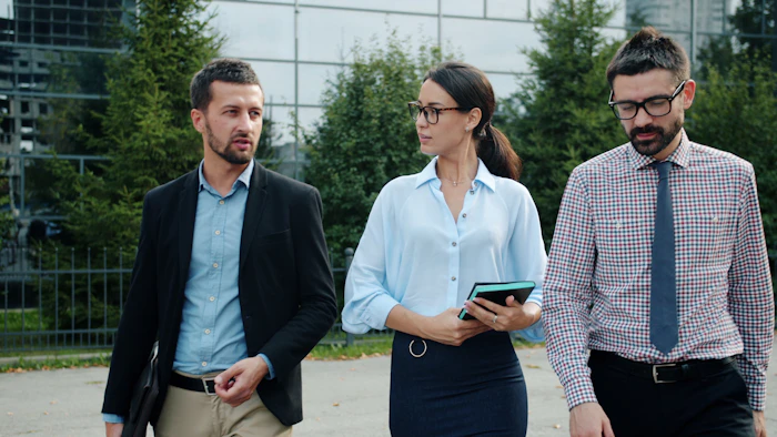 Three professionals walking and talking outside an office building