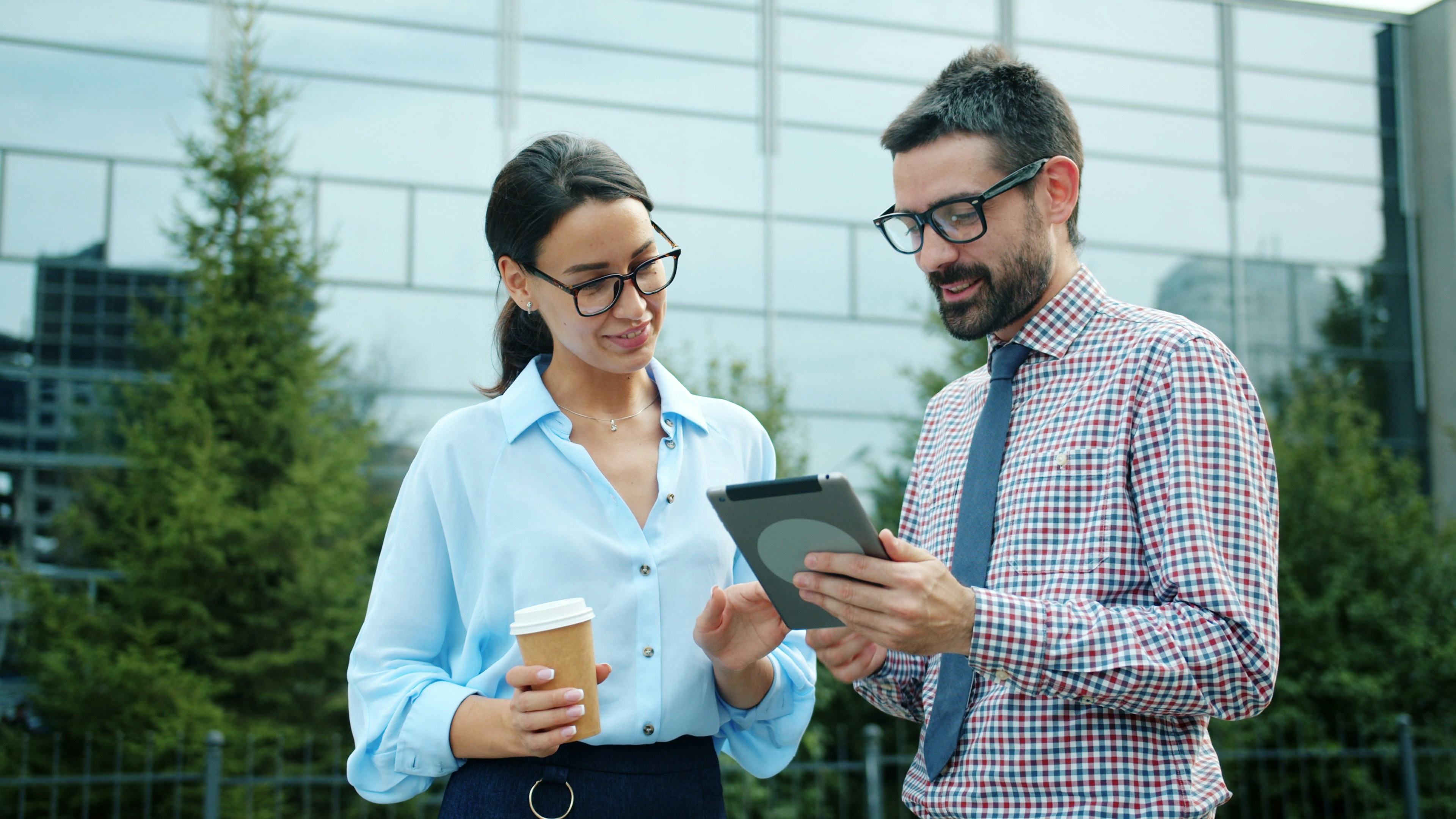 Two colleagues discussing a tablet outdoors