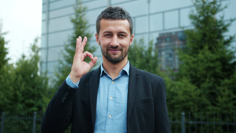 一位身穿西装的男士微笑着比出“OK”手势，自信满满