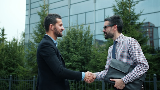 Two businessmen shaking hands outside modern building