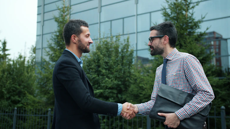 Two businessmen shaking hands outside modern building