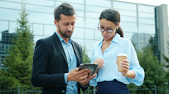 Two business people looking at a tablet outside.