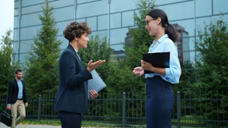 Two businesswomen talking outside modern office building.