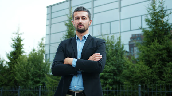 Marcus J. Hartwell, founding partner, arms crossed outside the firm's office building in a navy blazer