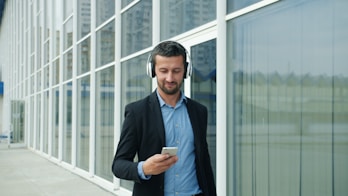 Man in suit listening to music on headphones outside