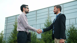 Two businessmen shaking hands outside modern building