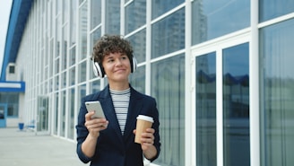 Woman with headphones holding phone and coffee cup