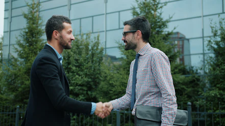 Two businessmen shaking hands outside an office building