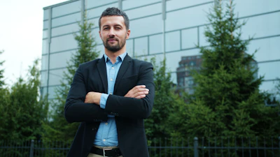 Man in suit standing with arms crossed outdoors