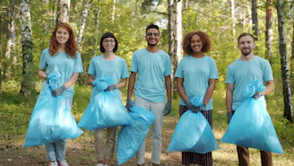Diverse volunteers holding trash bags in a forest