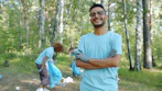 Man smiling in park with volunteers cleaning up.
