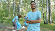 Man smiling in park with volunteers cleaning up.