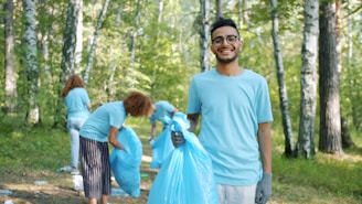 Volunteers cleaning up a forest with blue trash bags.