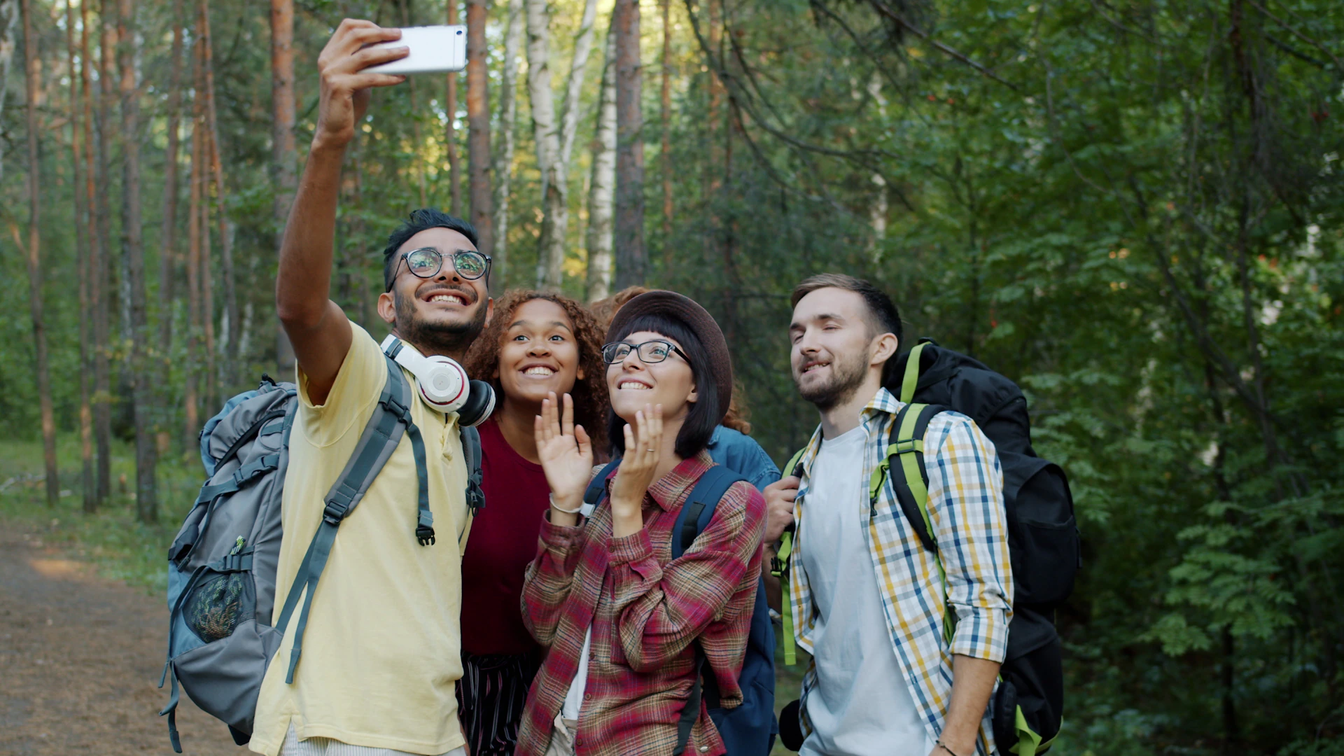 Four friends take a selfie while hiking in the forest.