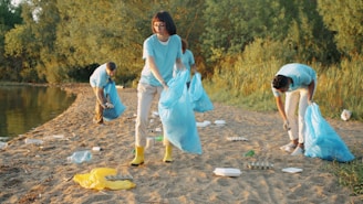 Volunteers collecting trash on a beach with blue bags.
