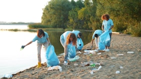 Volunteers cleaning up trash on a beach by the water.