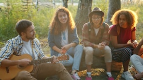 Friends gathered around campfire, playing guitar and singing