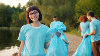 Young woman with volunteers cleaning beach with blue bags