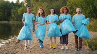 Diverse group of volunteers holding trash bags by water