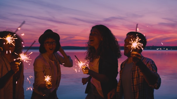 Friends celebrating with sparklers at sunset
