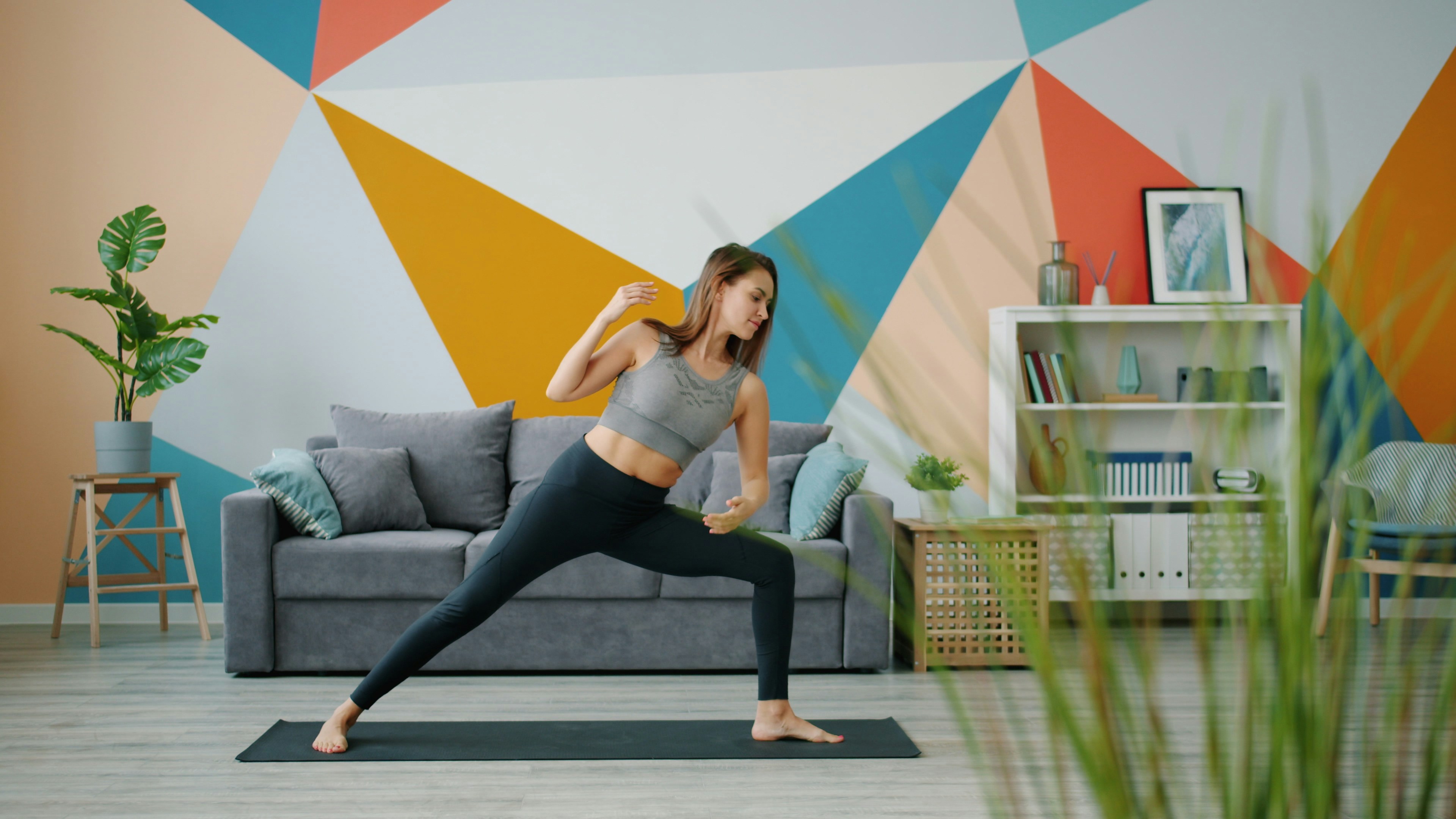 Woman practicing yoga in a brightly decorated living room.