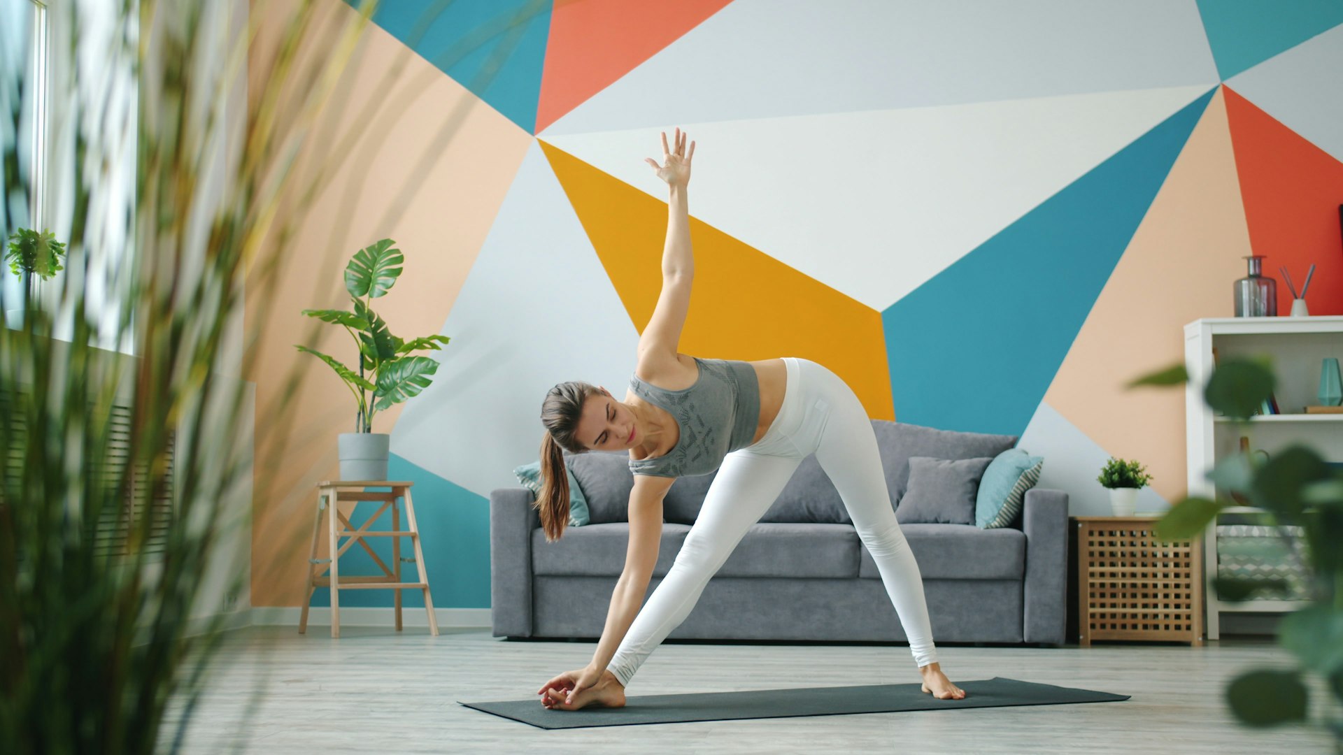 Woman in Extended Triangle Pose on a yoga mat in a bright living room