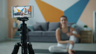 Woman recording fitness video on phone with tripod.
